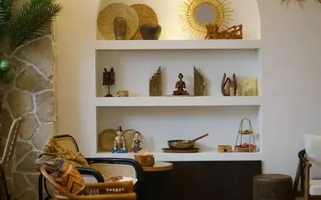 Rattan armchairs and carved wooden shelves of Balinese ornaments in the lounge of a Bali-style spa in Shanghai