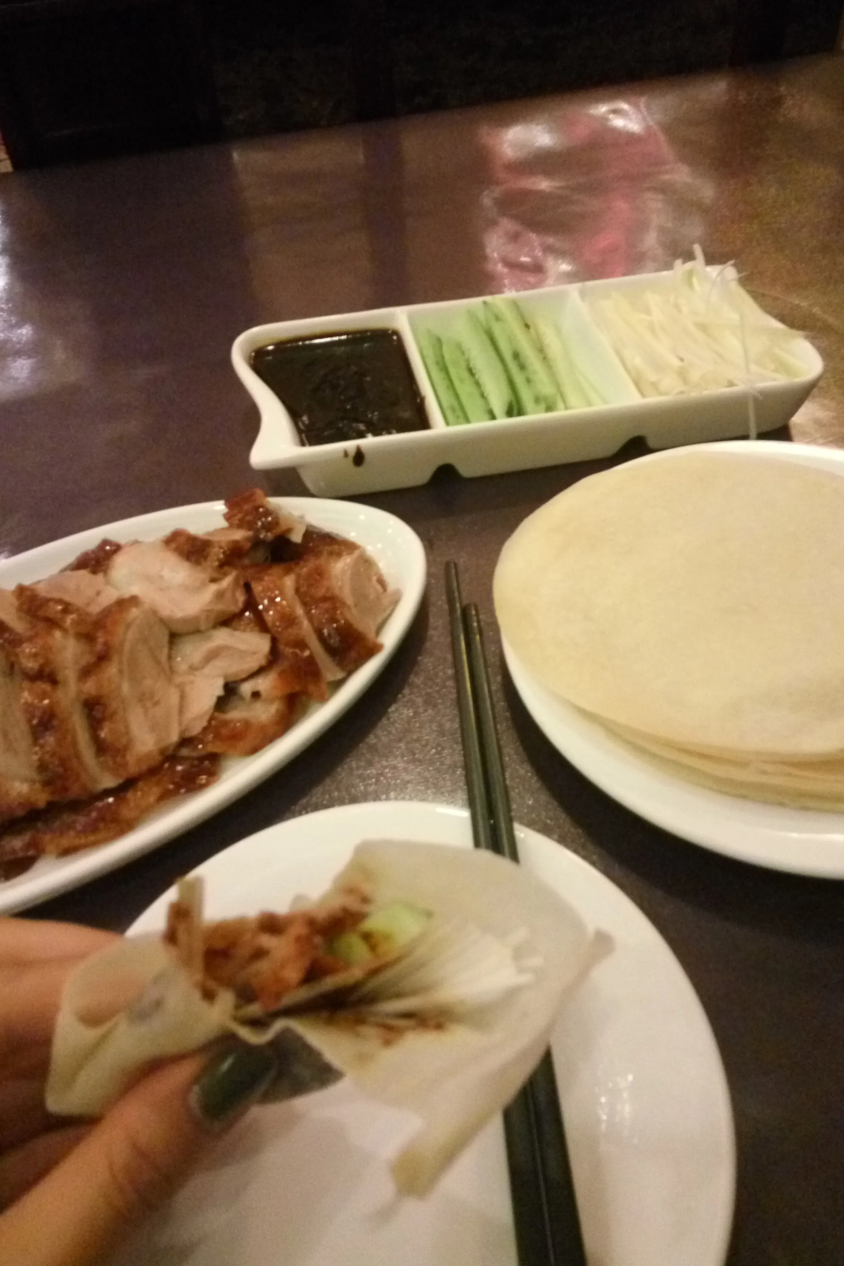 A table laid with Peking duck, pancakes and condiments