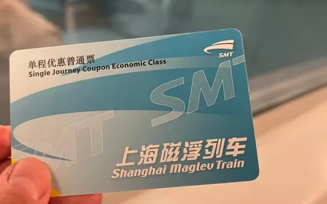 A hand holding a Shanghai Maglev single-journey ticket at the station