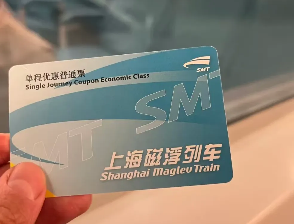 A hand holding a Shanghai Maglev single-journey ticket at the station