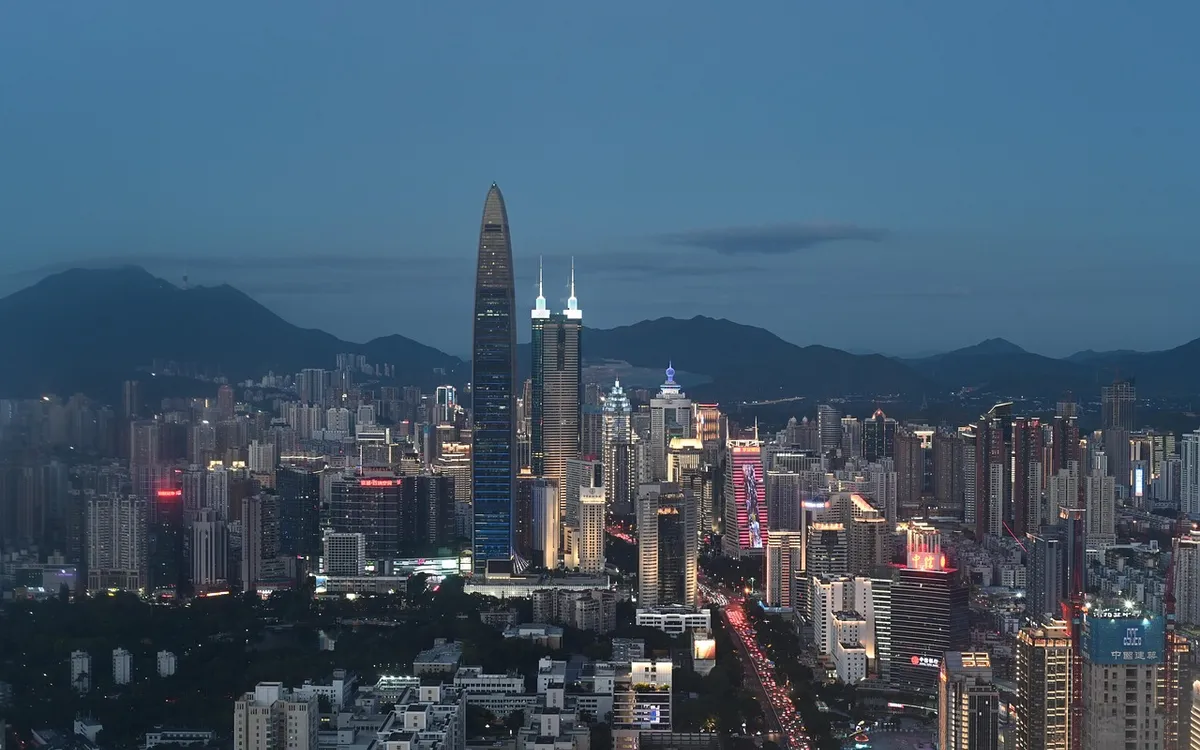 Shenzhen skyline at dusk, with illuminated towers and mountains in the background