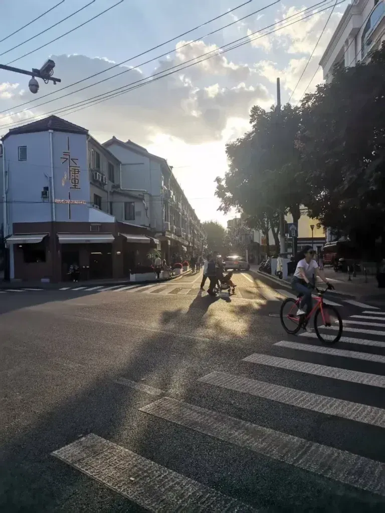 Late-afternoon light at Yongkangli, with a cyclist crossing in front of low-rise neighbourhood buildings