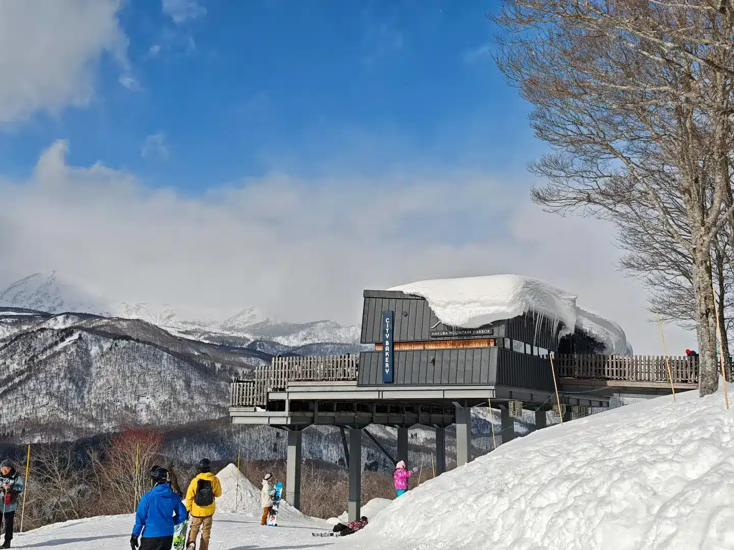 Skiing in Japan, Hakuba Valley ski resort with chairlifts and Olympic mountain peaks under a clear blue sky in Nagano